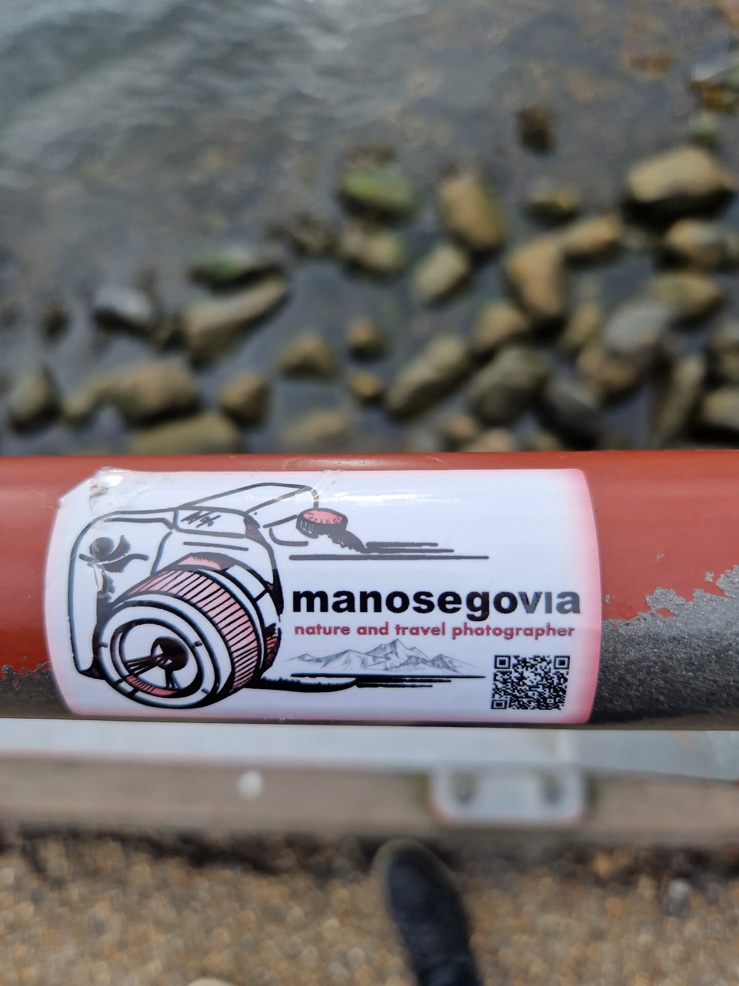 A sticker featuring a drawing of a camera, mountains, and a QR code. The text 'manosegovia nature and travel photographer' is prominently displayed.