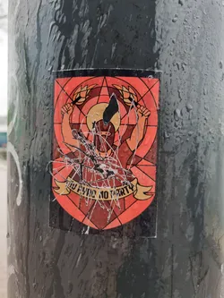 A sticker featuring an illustration of a person in a helmet holding axes, set within a stained-glass style design. The sticker shows some damage and water marks.