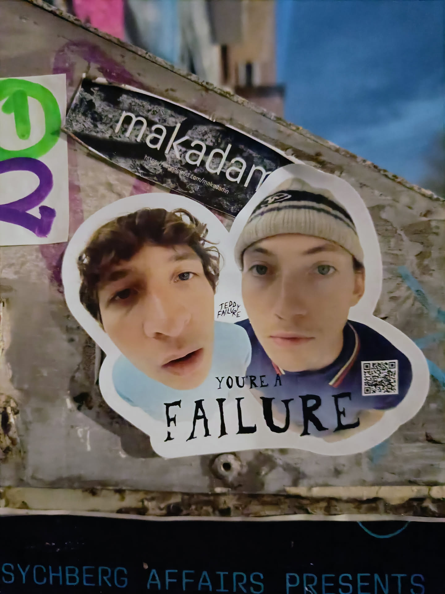 A sticker featuring two young men with the text "YOU'RE A FAILURE" below them.  There is a QR code in the bottom right corner.