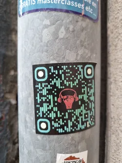 A sticker featuring a QR code with a stylized bull wearing headphones in the center. The QR code is teal and black, and the bull is red.