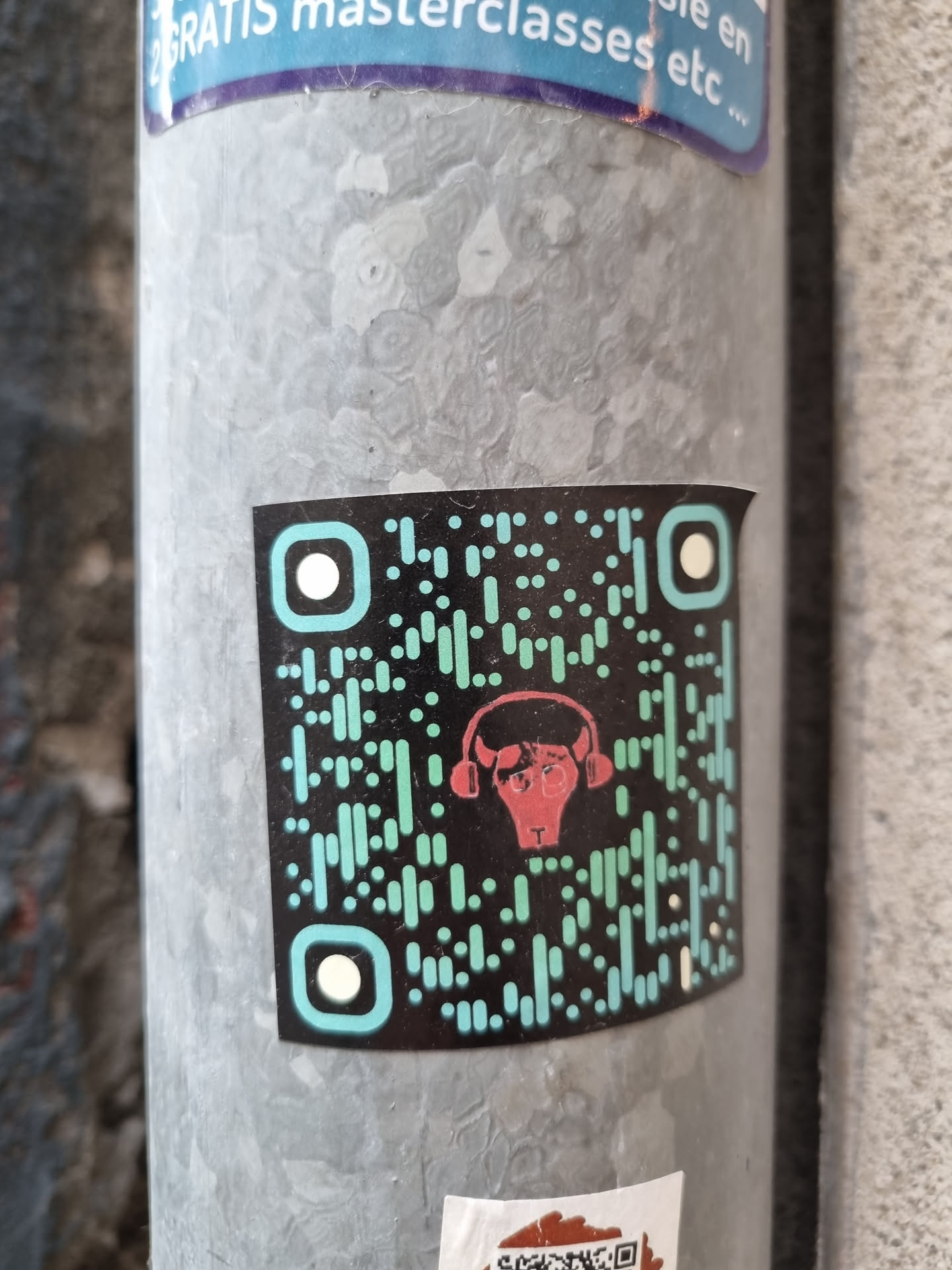 A sticker featuring a QR code with a stylized bull wearing headphones in the center. The QR code is teal and black, and the bull is red.