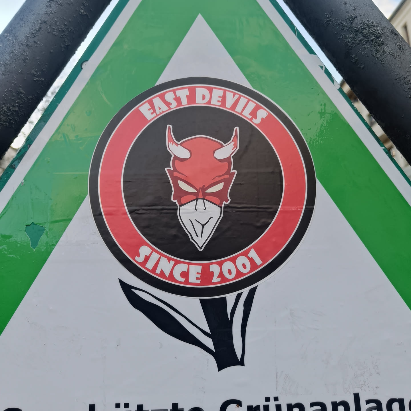 A round sticker featuring a devil mascot with the text 'East Devils Since 2001'. The sticker is affixed to a triangular sign.