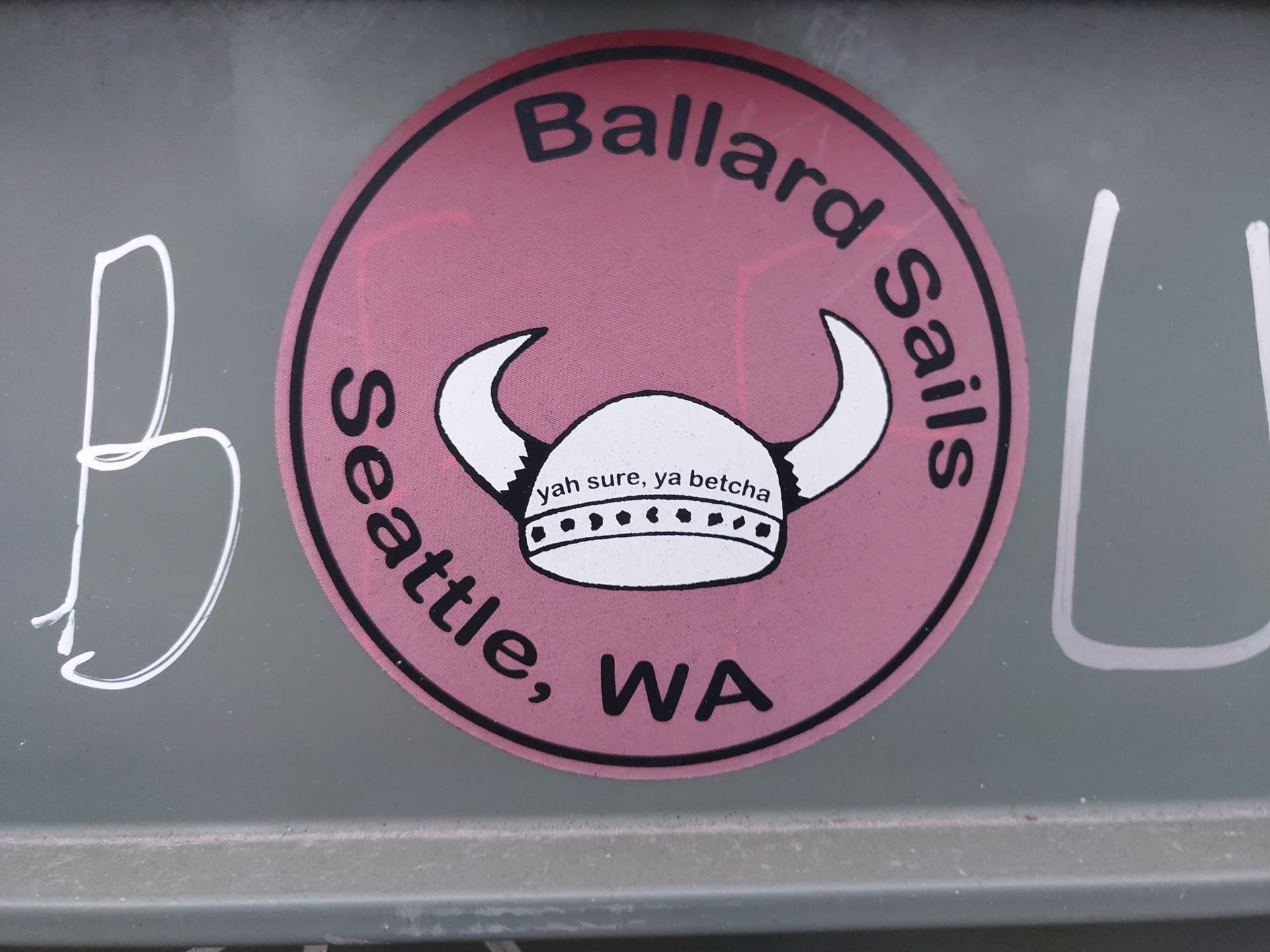 Round pink sticker with a Viking helmet graphic and text. It says "Ballard Sails" at the top and "Seattle, WA" at the bottom. Inside the circle is a Viking helmet with the text  "Yah sure, ya betcha"