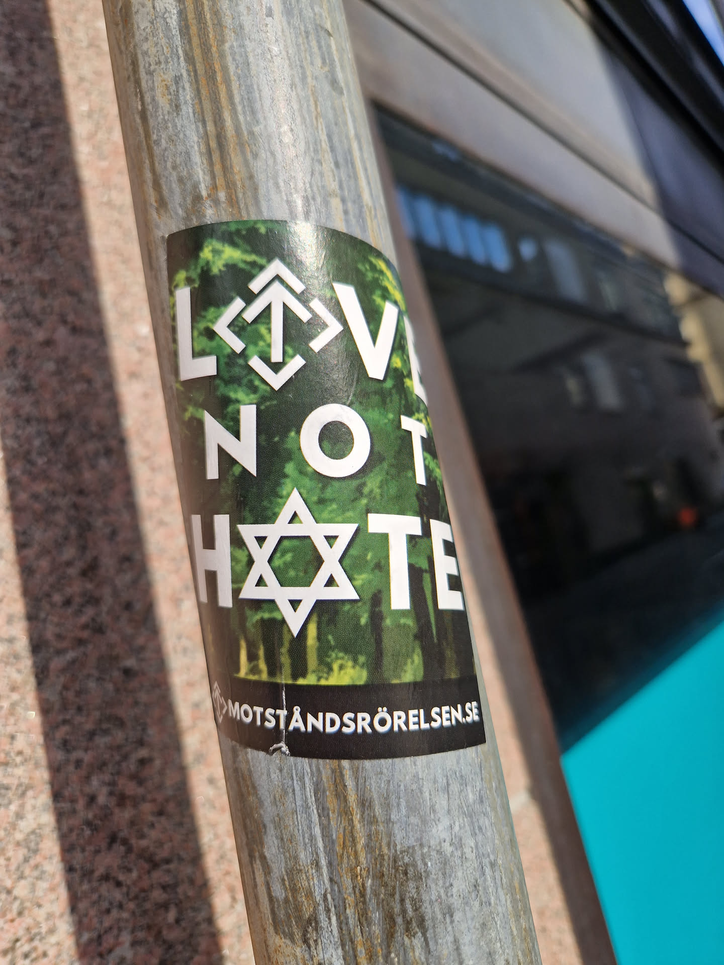 A sticker with a message of love and tolerance, featuring a Star of David and a forest background.  The text also includes a website address.