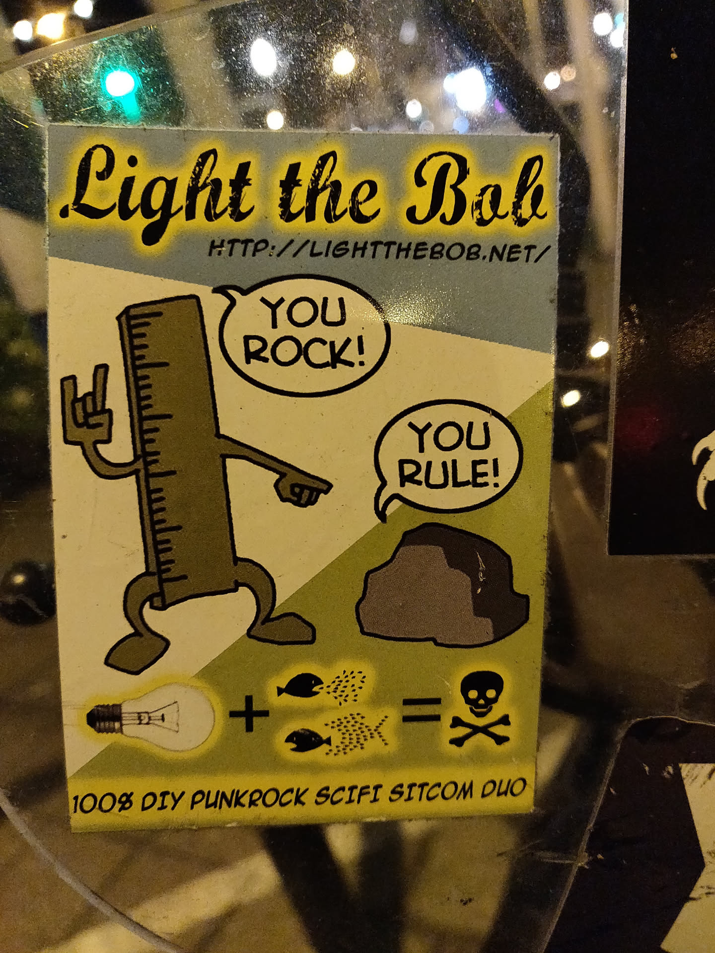 A sticker featuring a ruler character, a rock, lightbulb, fish, and a skull and crossbones. It has a website address and the phrases "You Rock!" and "You Rule!"