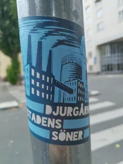 A sticker depicting an industrial landscape with factories and smokestacks in a blue and white color scheme.  The text "Djurgårdens söner" is prominently displayed at the bottom. The style is reminiscent of vintage printmaking or linocut.