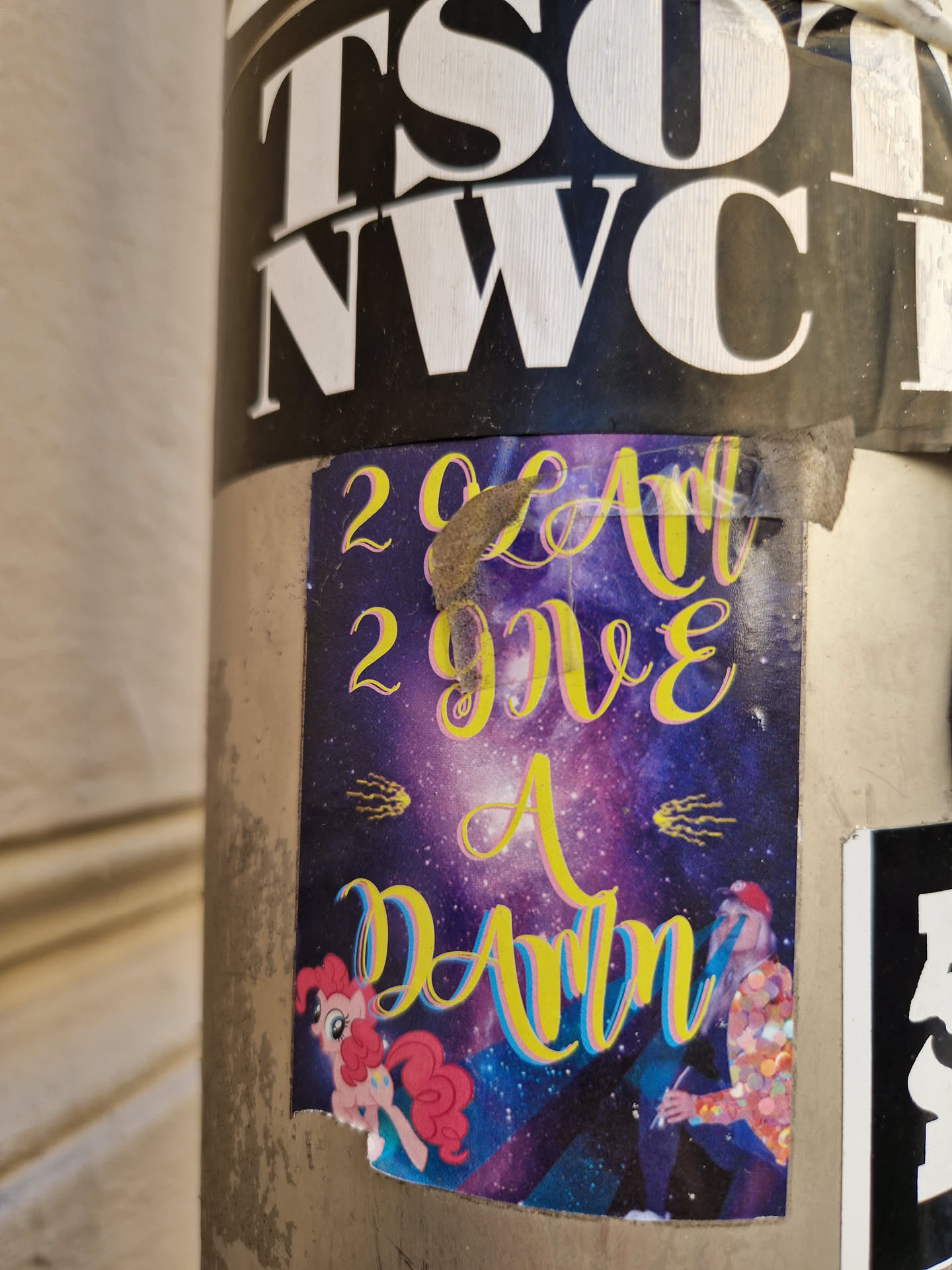 A sticker with a space theme, featuring the text "2023 Art 2 give a damn" in yellow on a purple background.  There are also cartoonish depictions of My Little Pony and a person seemingly drawing or painting. 