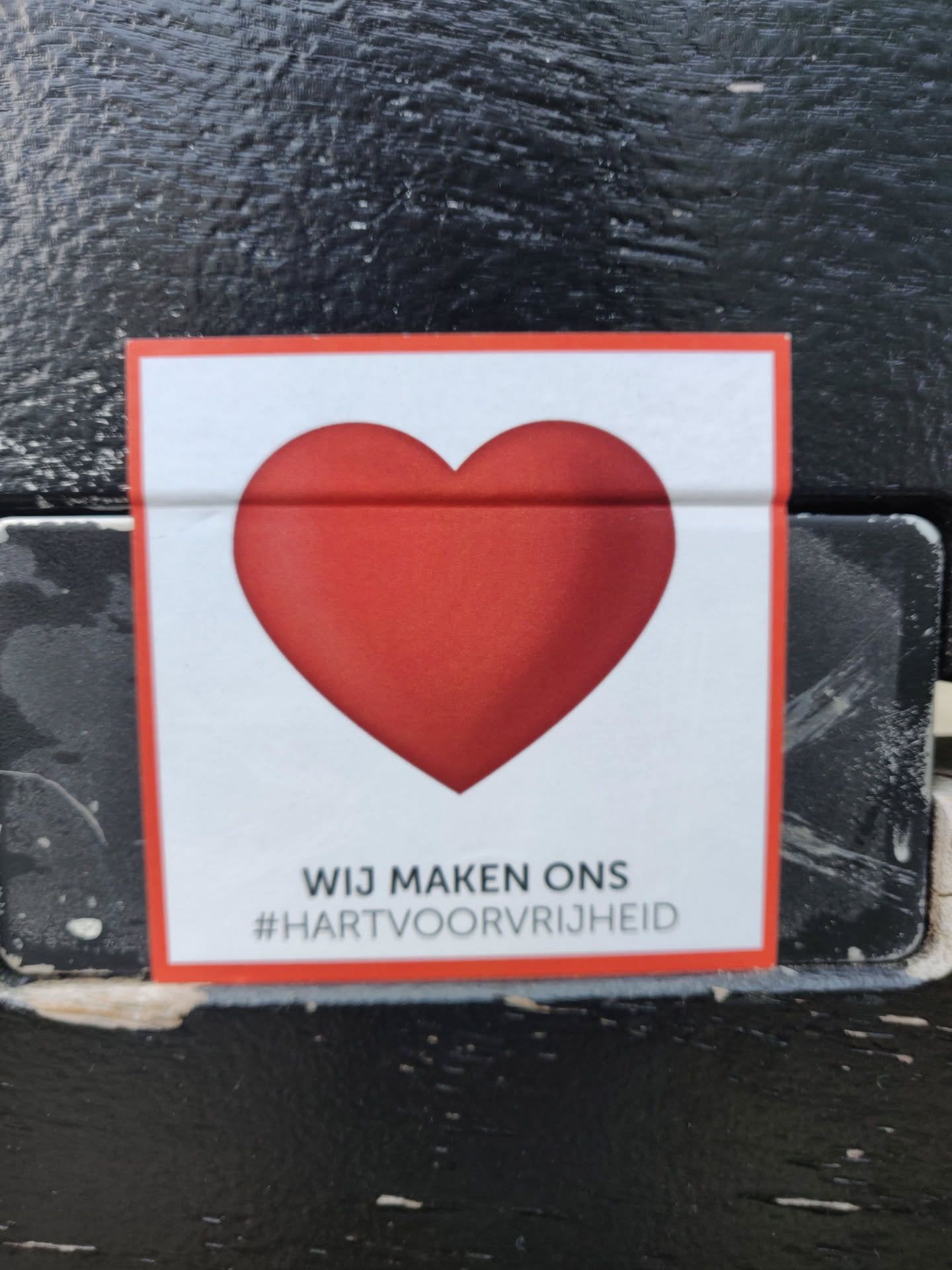 A sticker with a red heart and the text "Wij maken ons #hartvoorvrijheid" which translates from Dutch to English as "We make our hearts for freedom".