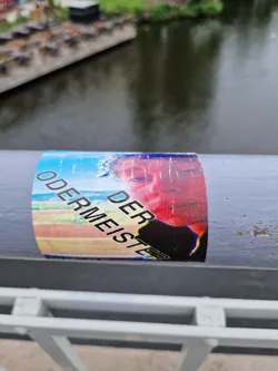 A sticker featuring a stylized portrait and text that appears to say "Der Odermeister". The style is reminiscent of glitch art or digital distortion.