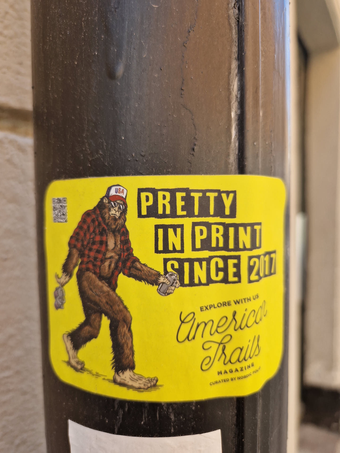 Yellow sticker featuring a Bigfoot illustration holding two spray cans. Text on the sticker includes "Pretty in print since 2017" and "American Trails Magazine".