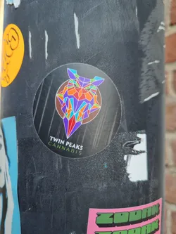 A round sticker featuring a colorful geometric owl design. The text below the owl says "Twin Peaks Cannabis".