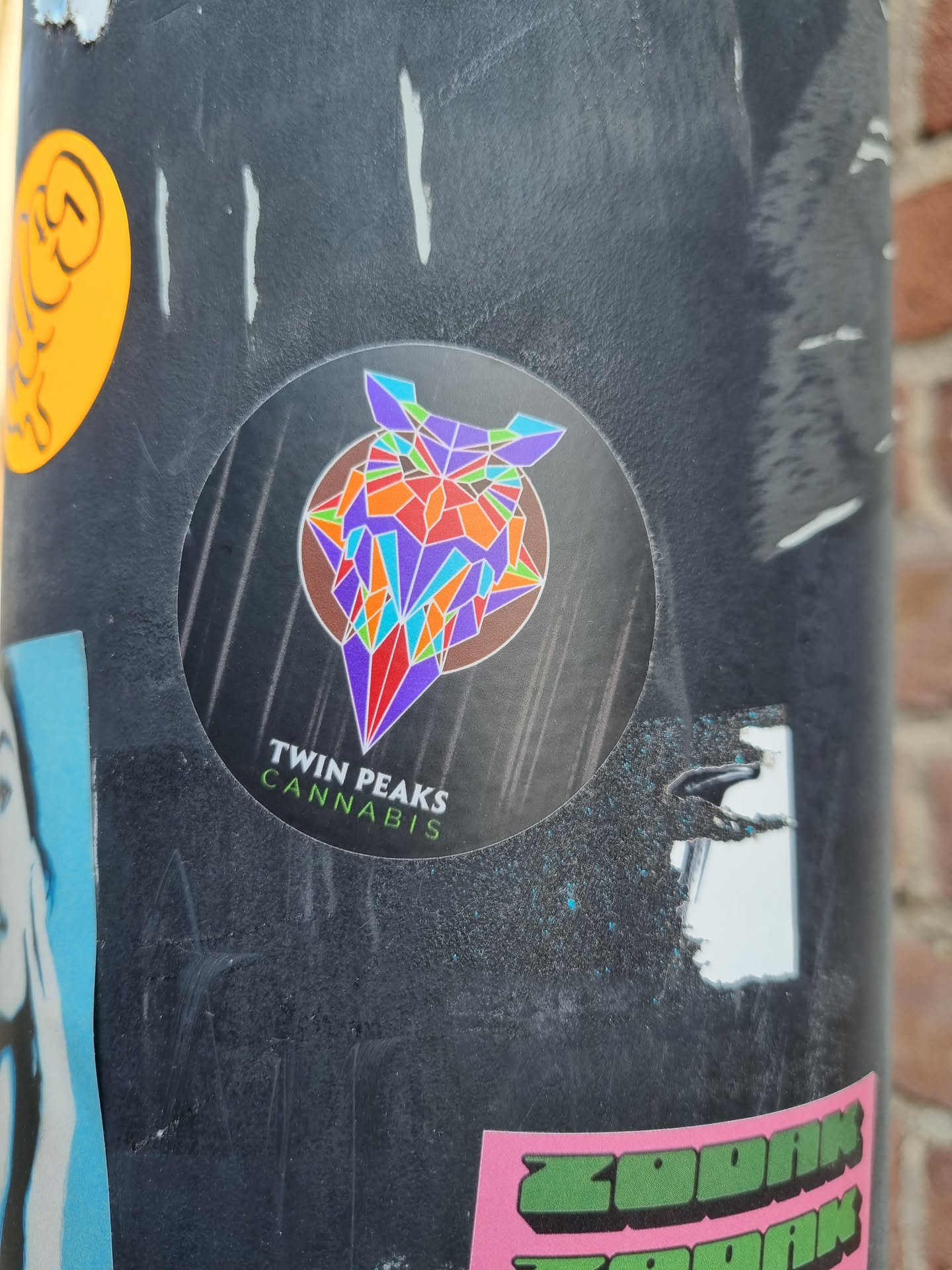 A round sticker featuring a colorful geometric owl design. The text below the owl says "Twin Peaks Cannabis".