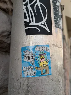A sticker featuring a cartoon character smoking a joint with a skull in the background. The text "Most Dope" and "Senir" is written on it. The sticker is on a pole.