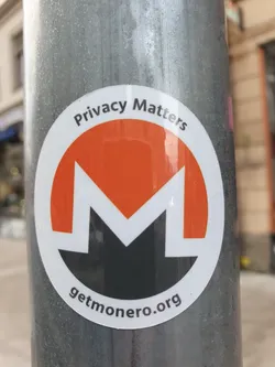 A round Monero sticker affixed to a metal pole. The sticker features the Monero logo, the text "Privacy Matters" at the top, and "getmonero.org" at the bottom.