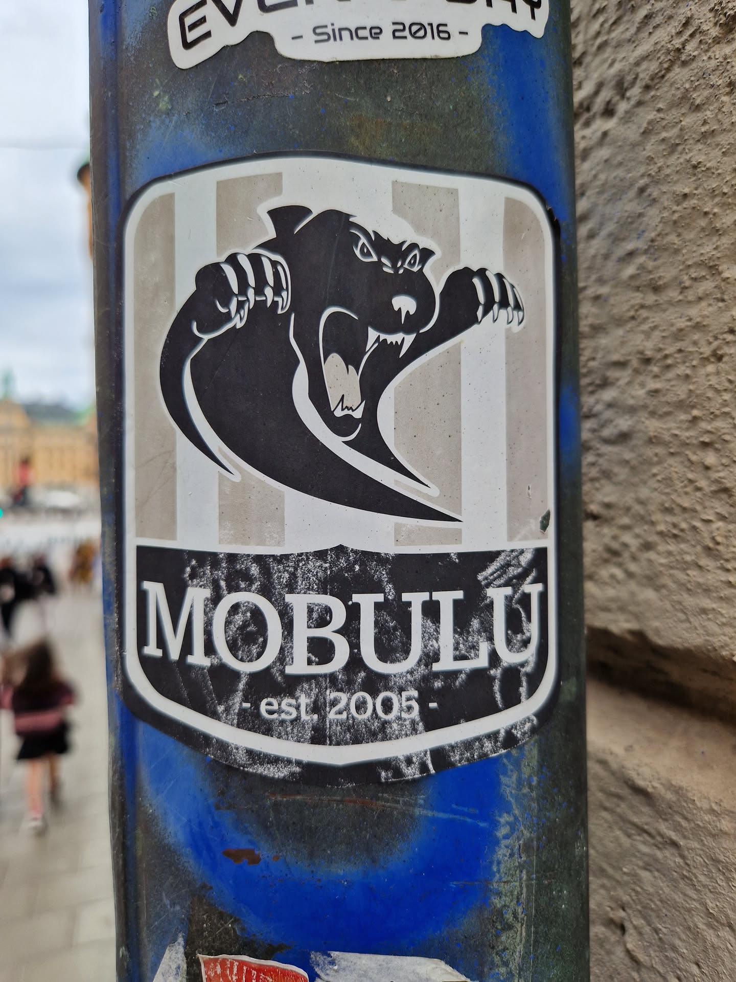 A sticker featuring a black panther-like creature with claws outstretched. The background is light grey with vertical stripes.  The text 'MOBULU' is prominently displayed below the creature, with '- est 2005 -' underneath.