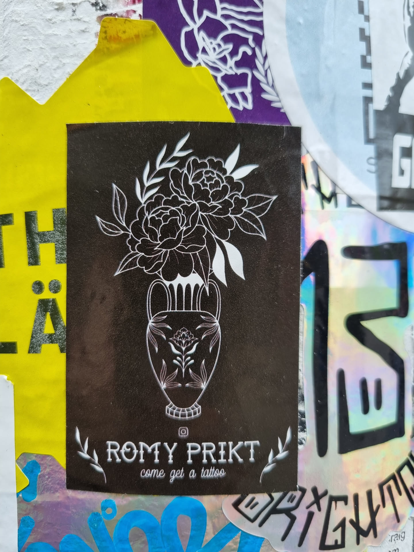 Black and white sticker featuring a line art drawing of peonies in a vase.  The sticker advertises tattoo services by the artist Romy Prikt.