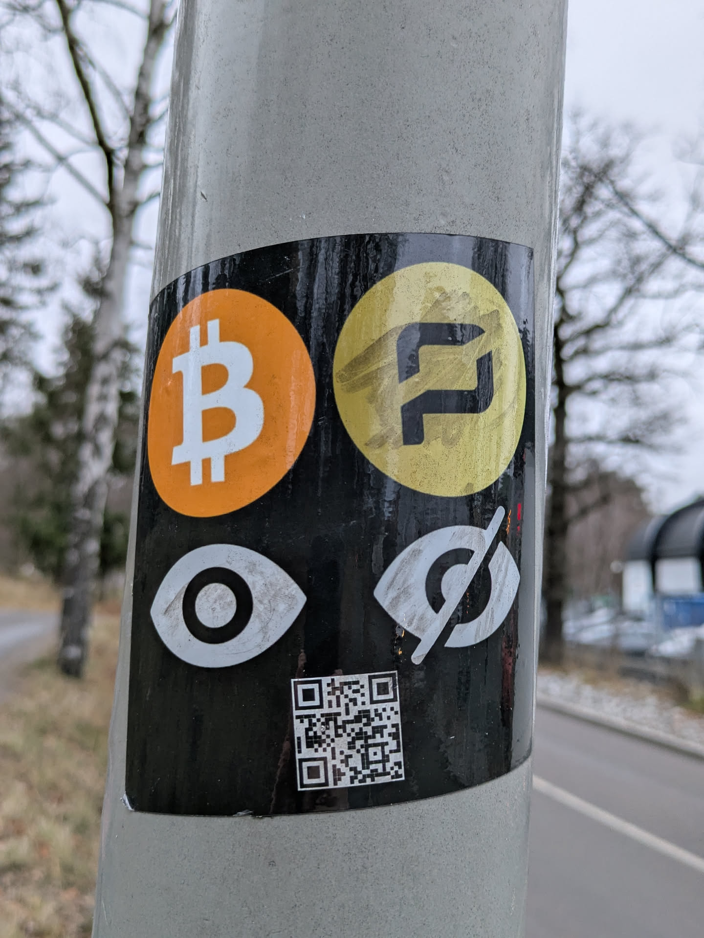 A sticker featuring Bitcoin (BTC) and Monero (XMR) symbols, along with eye icons representing privacy.  A QR code is also present at the bottom.