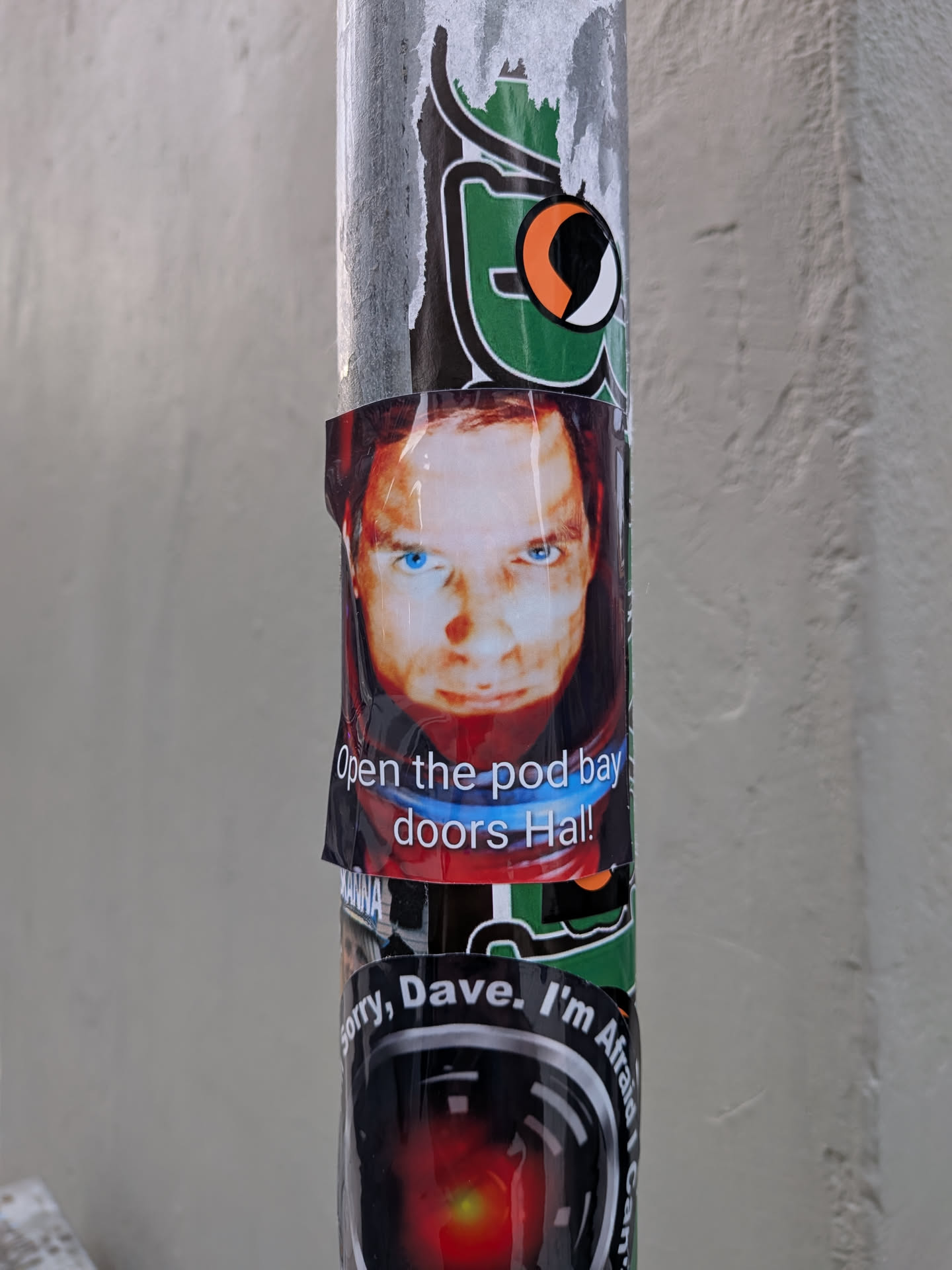 A rectangular glossy sticker featuring a close-up still of Dr. David Bowman (portrayed by Keir Dullea) wearing a red spacesuit helmet from the film '2001: A Space Odyssey'. His face is illuminated from below, highlighting his intense gaze and bright blue eyes. Across the lower portion of his visor and suit collar, the famous quote 'Open the pod bay doors Hal!' is printed in clean, white sans-serif text with a subtle dark outline.