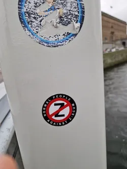 A round sticker with a red circle and a slash over the letter Z. The text around the circle says "NORMAL PEOPLE AGAINST Z SCUM".