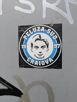 The sticker features a black and white portrait of a man inside a blue and white circle. The text 'PELUZA-SUD' and 'CRAIOVA' are printed in bold letters around the circle, with the years '19' and '97' flanking the portrait.