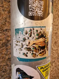 A sticker featuring a stylized illustration of a powerful fist shattering stone. The art style is reminiscent of comic books or graphic novels, with bold lines and vibrant colors. The sticker is affixed to a metal pole, likely in an outdoor urban setting.