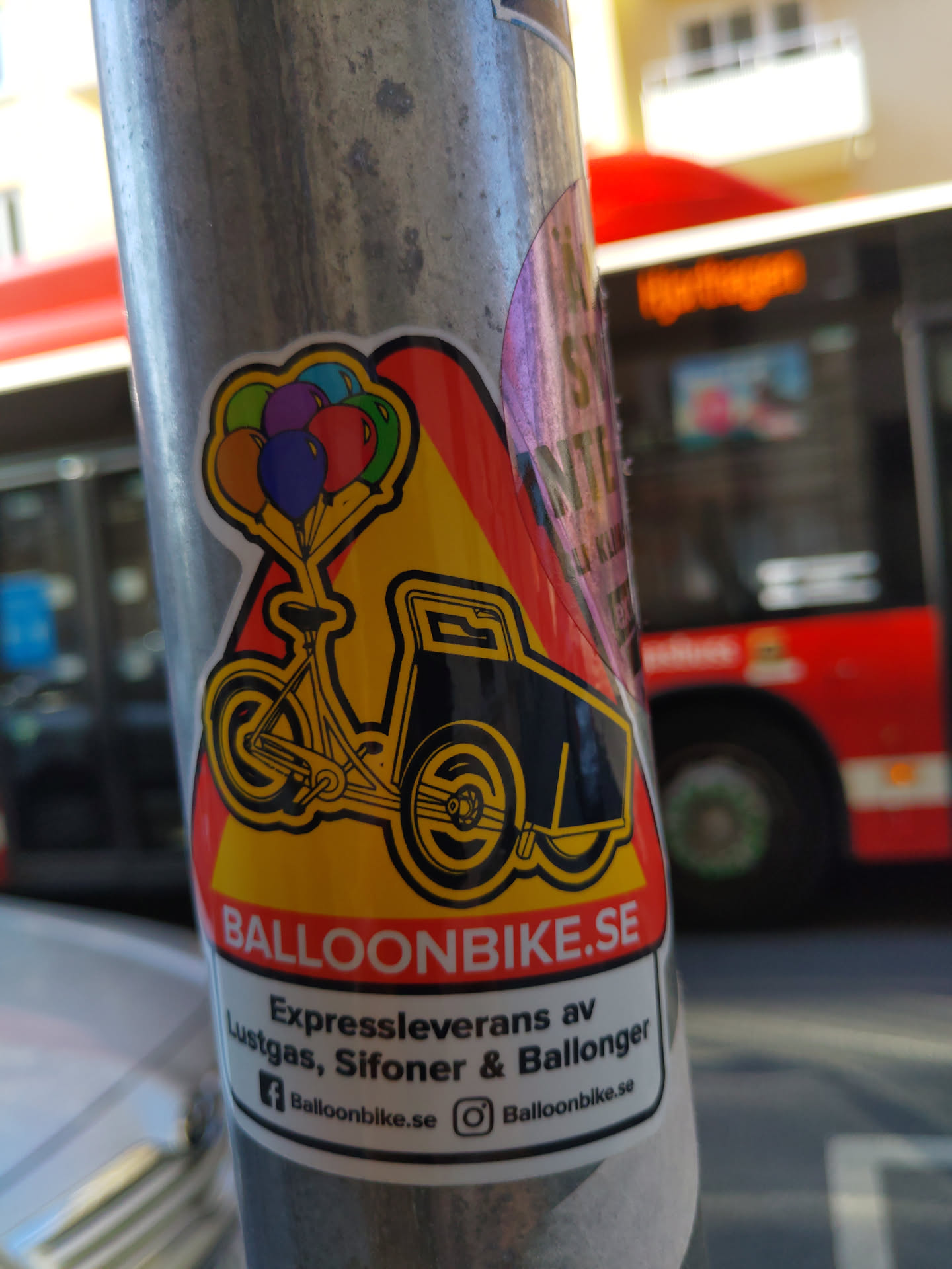 Sticker featuring a cartoon illustration of a bicycle with balloons, advertising a delivery service for helium, siphons, and balloons.  The sticker includes the website address and social media links.