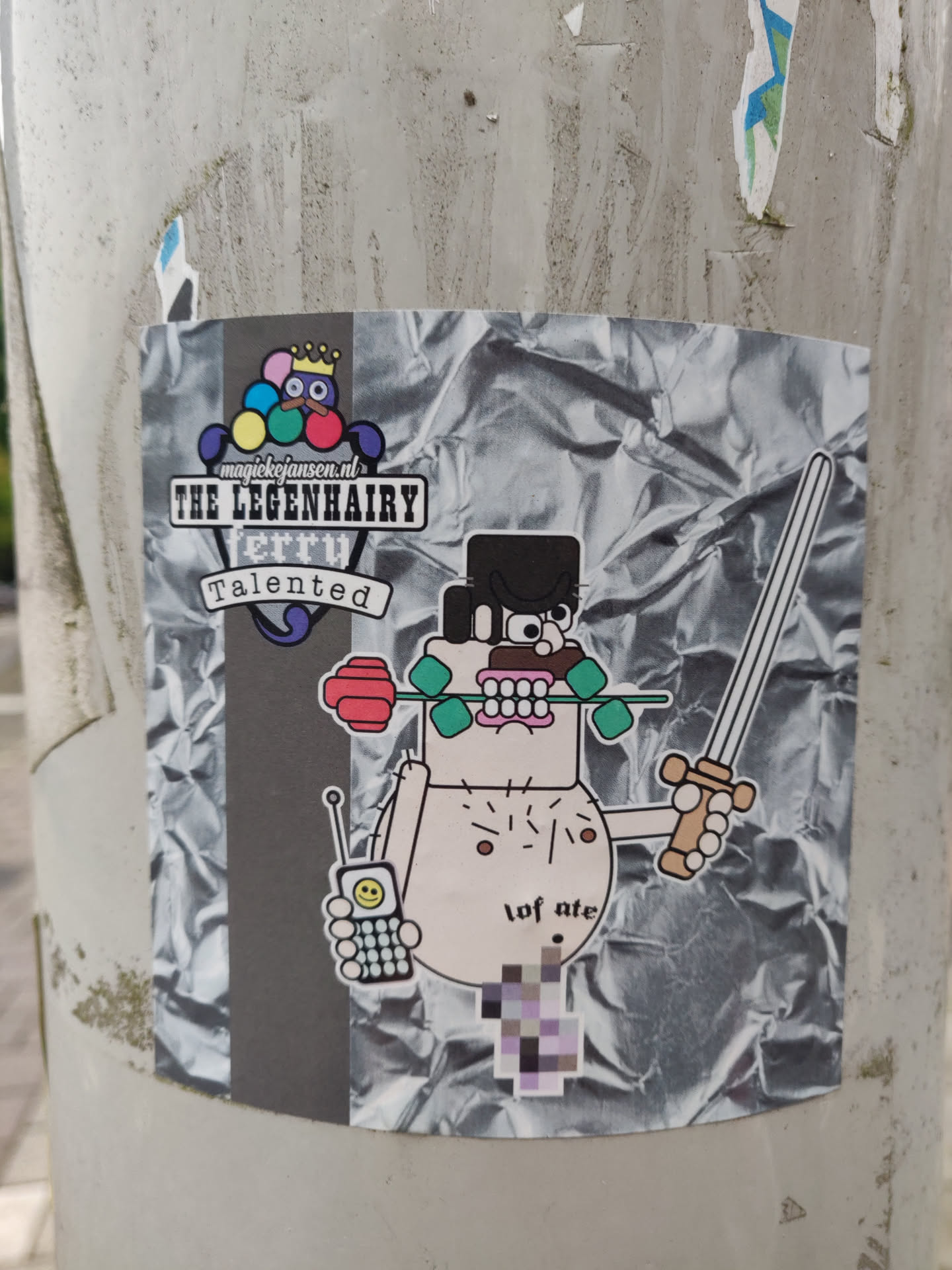 A sticker featuring a cartoon character holding a sword and a rose, with a cell phone in his other hand. The character's style is simplistic, with bold outlines and flat colors. The background of the sticker is a crumpled silver foil, giving it a street art aesthetic.  The text on the sticker includes 'THE LEGENHAIRY terry' and 'Talented'. A website address is also visible: magickrijgers.nl