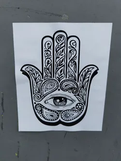 Black and white sticker of a Hamsa hand with an eye in the center, decorated with paisley and floral patterns. 