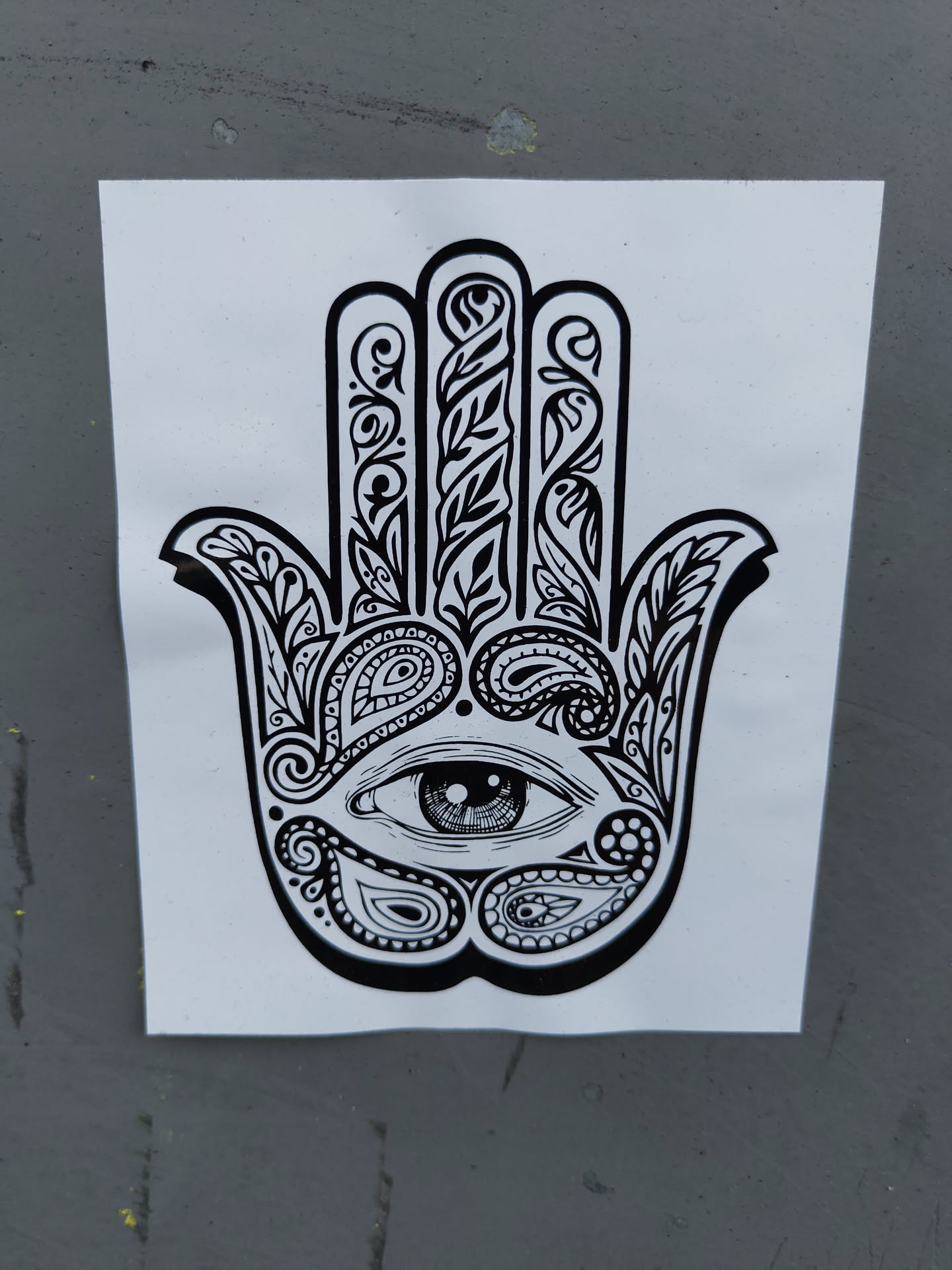 Black and white sticker of a Hamsa hand with an eye in the center, decorated with paisley and floral patterns. 