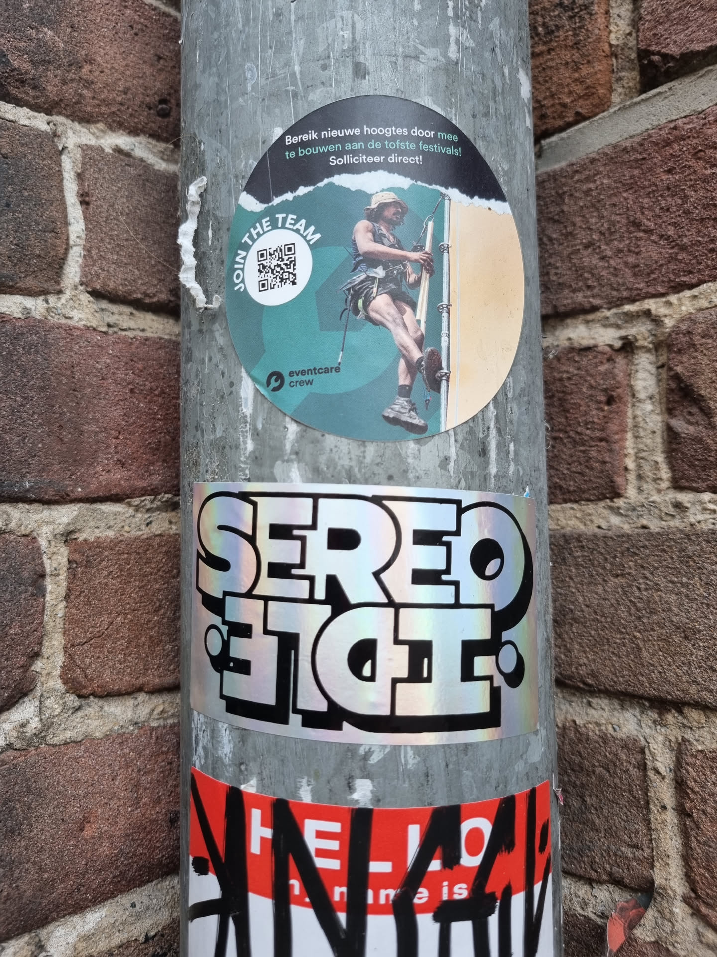 Holographic sticker with the text SEREO ET CIE. The sticker has a iridescent finish and is attached to a metal pole.