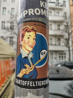 Street sticker A vintage-style sticker featuring a smiling housewife holding a spoon with a cute, cartoonish character at the end.  The text at the bottom says "Kartoffeltierchen" which translates to potato dumplings.  The text at the top says "Alles Lecker!" meaning "Everything is delicious!"