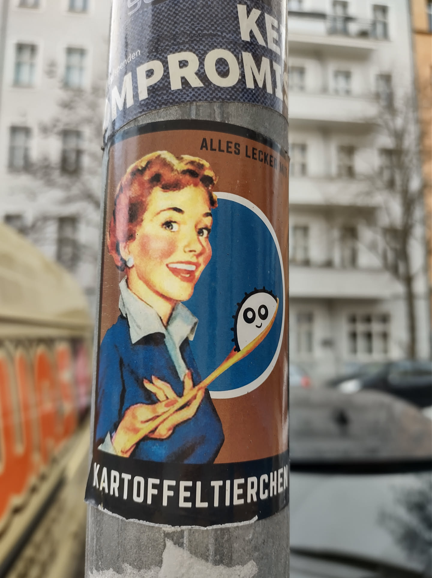 A vintage-style sticker featuring a smiling housewife holding a spoon with a cute, cartoonish character at the end.  The text at the bottom says "Kartoffeltierchen" which translates to potato dumplings.  The text at the top says "Alles Lecker!" meaning "Everything is delicious!"