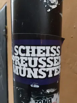 A sticker with the text "Scheiss Preussen Munster" on a purple background. The text is in bold, white uppercase letters.