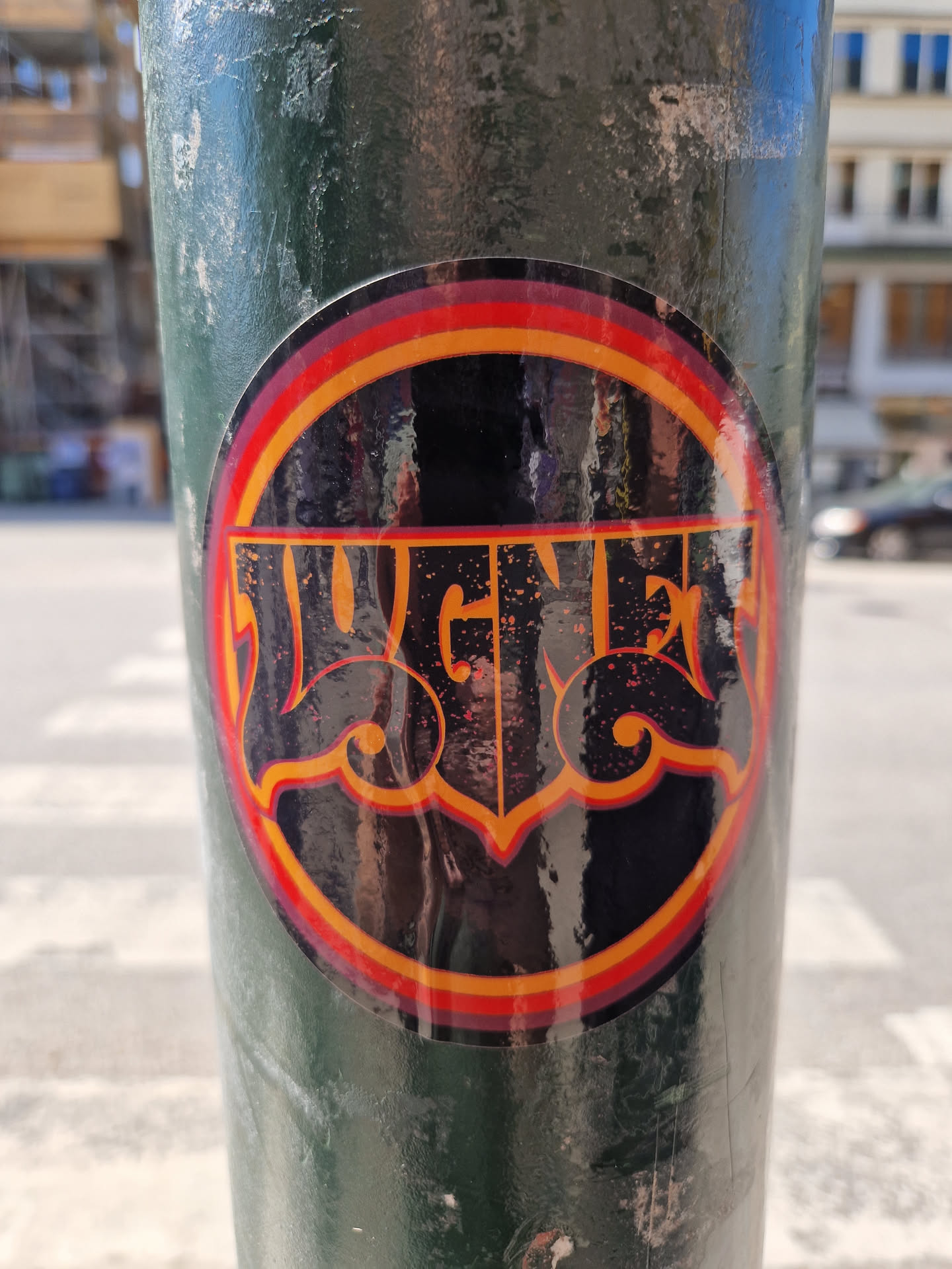 A round sticker featuring the word "Jugger" in a stylized, retro font with orange and red accents. The sticker is affixed to a dark green pole and appears glossy.