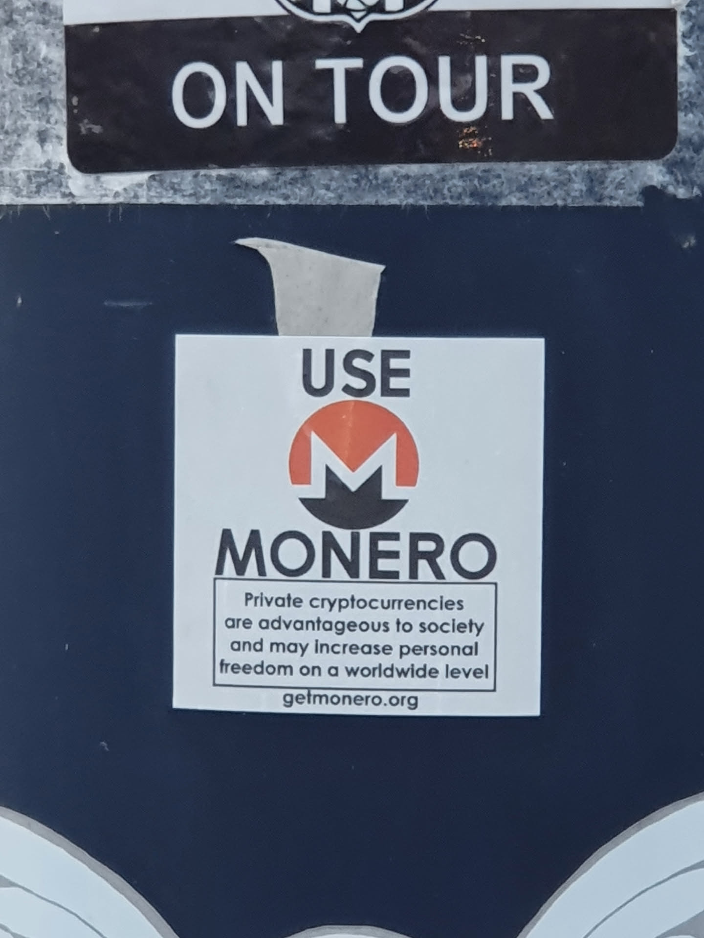 A sticker promoting Monero, a privacy-focused cryptocurrency.  The sticker features the Monero logo and text that highlights the advantages of private cryptocurrencies for society and personal freedom.  A website URL is included.