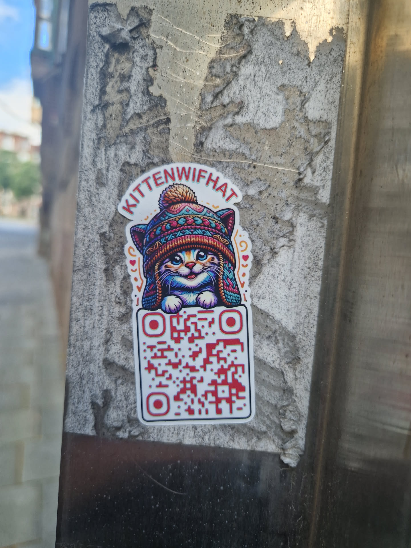 A cute kitten wearing a winter hat. The sticker also includes a QR code.