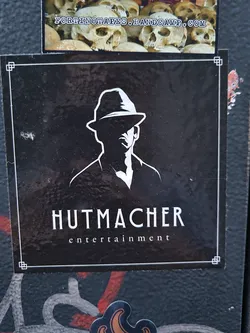 Black and white sticker featuring a silhouette of a man in a fedora hat. The text 'Hutmacher entertainment' is written below the image.
