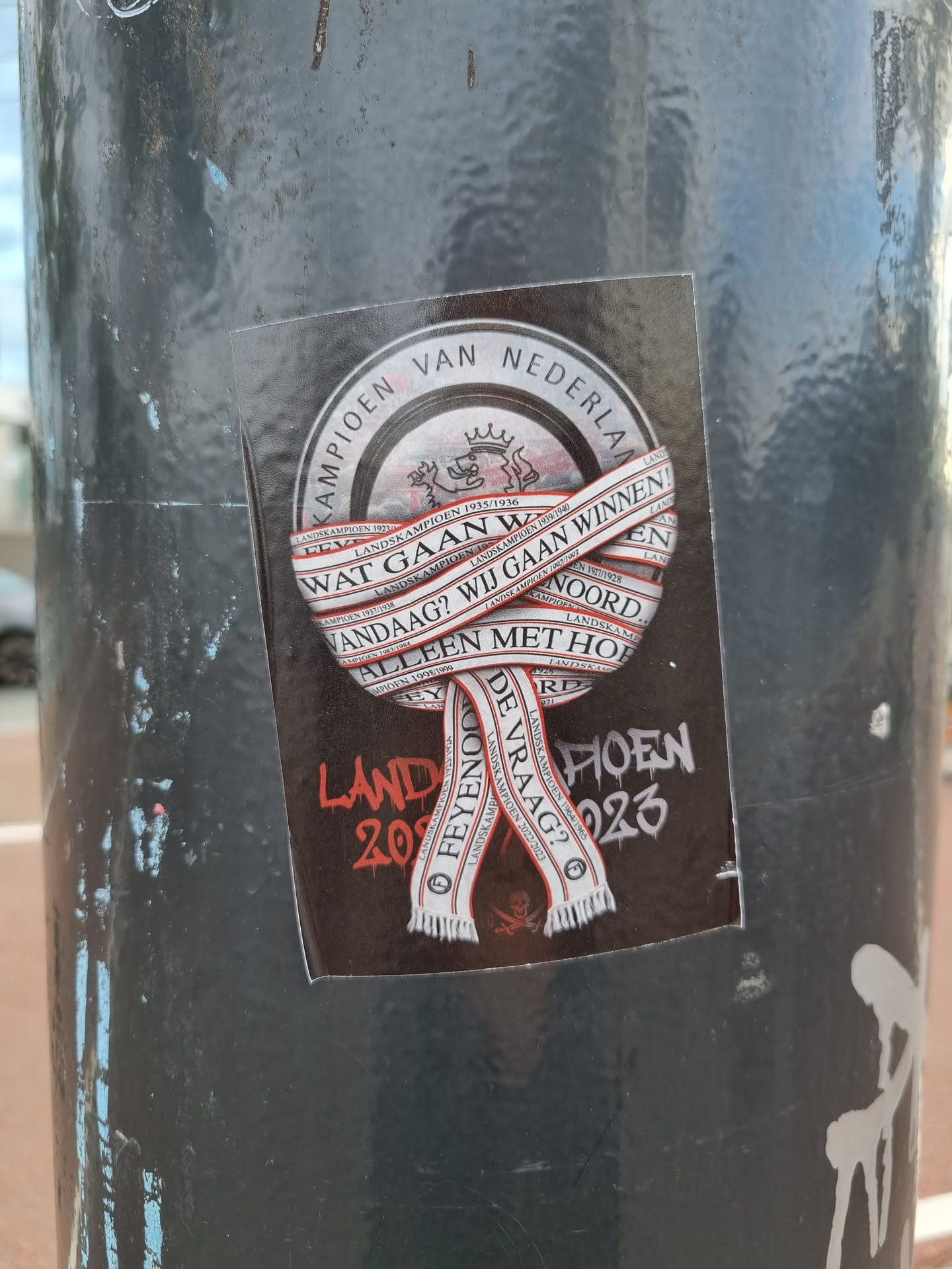 A sticker celebrating Feyenoord's championship win in the Netherlands. The design features a circular emblem with the text "Kampioen van Nederland" and a scarf with the question "Wat gaan we vandaag?" (What are we going to do today?). Additional text on the sticker includes "alleen met hoop" (only with hope) and "de vraag?" (the question?). The year 2023 is also visible.