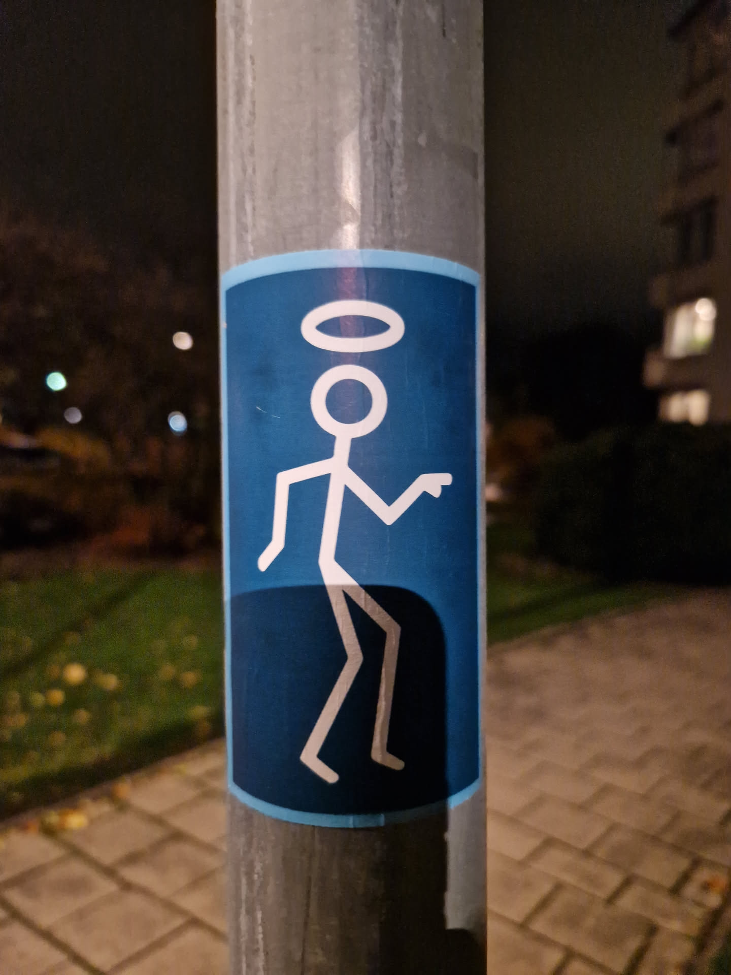 A blue sticker featuring a simple stick figure design. The figure appears to be dancing and has a halo above its head.  The style is minimalistic and playful.
