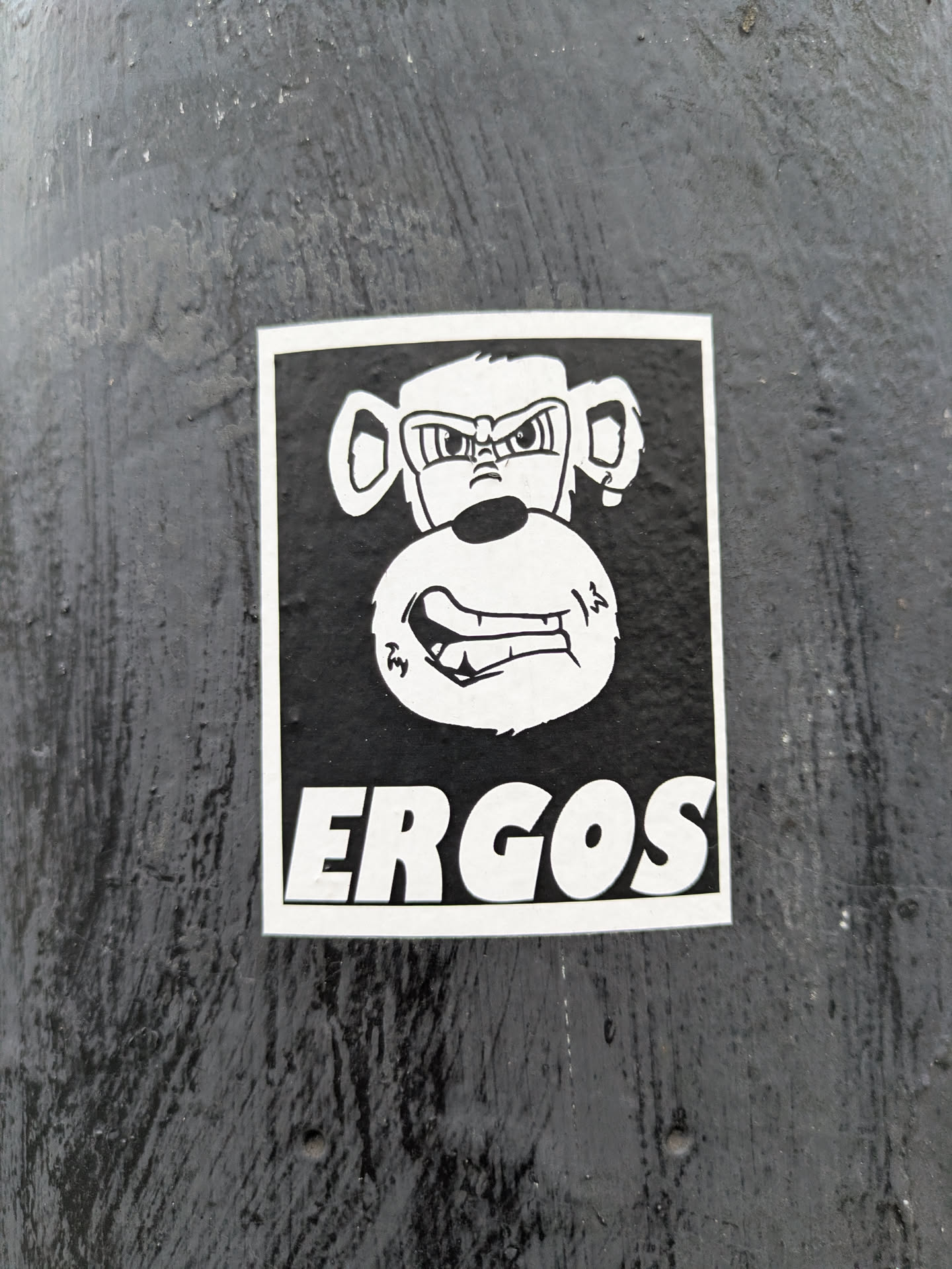 Black and white sticker featuring an angry monkey illustration with the word ERGOS written below it.