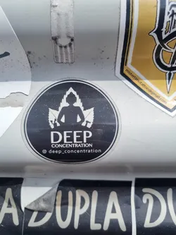 Black and white round sticker with a figure meditating in the middle of cannabis leaves. The text "DEEP CONCENTRATION" is written below the figure.  A social media handle is visible at the bottom.