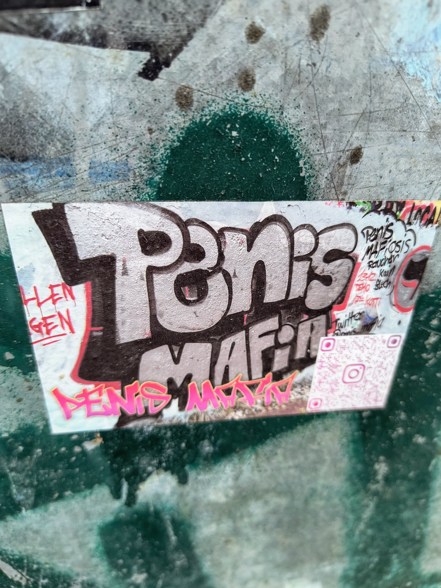 The sticker features "Penis Mafia" in bold, graffiti-style lettering with a pink outline. It also includes a QR code and the Instagram logo, suggesting a social media presence. There are also additional tags and text on the sticker, adding to its overall design.