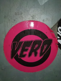 A round sticker with a pink background and a black ring around the edge. Inside the ring, the word \"VERO\" is written in a bold, stylized black font.