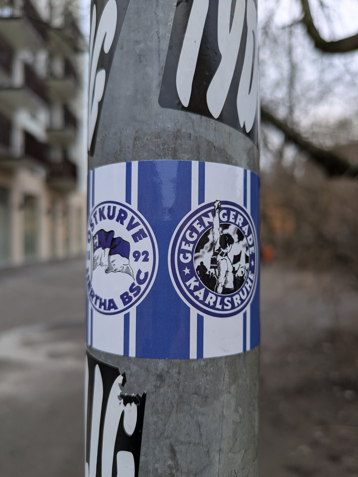 A sticker featuring the logo of "Gegengerade 92", a fan club of Karlsruher SC (Karlsruher Sport-Club). The design includes blue and white stripes with two circular logos, one showing a stylized representation of the club's crest and the other potentially depicting a scene from a football match. The text includes "Gegengerade" and "92".