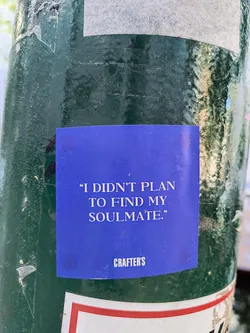 A blue sticker on a green pole reads, "I DIDN'T PLAN TO FIND MY SOULMATE." and "Crafter's" is written on the bottom right corner of the sticker.