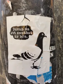 A sticker featuring a pigeon and Swedish text that translates to: "The pigeon said that snuthat is good."  The sticker is slightly torn. The meaning of "snuthat" is unclear without further context.