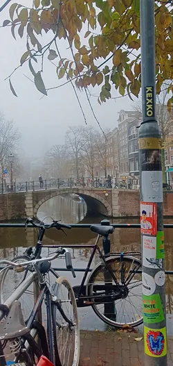 The sticker on the lamppost feature various designs, from text-based statements to colorful graphics. One sticker is red with a drawing and the text "CHILL MAL BERLIN". The bottom sticker is abstract and colourful.