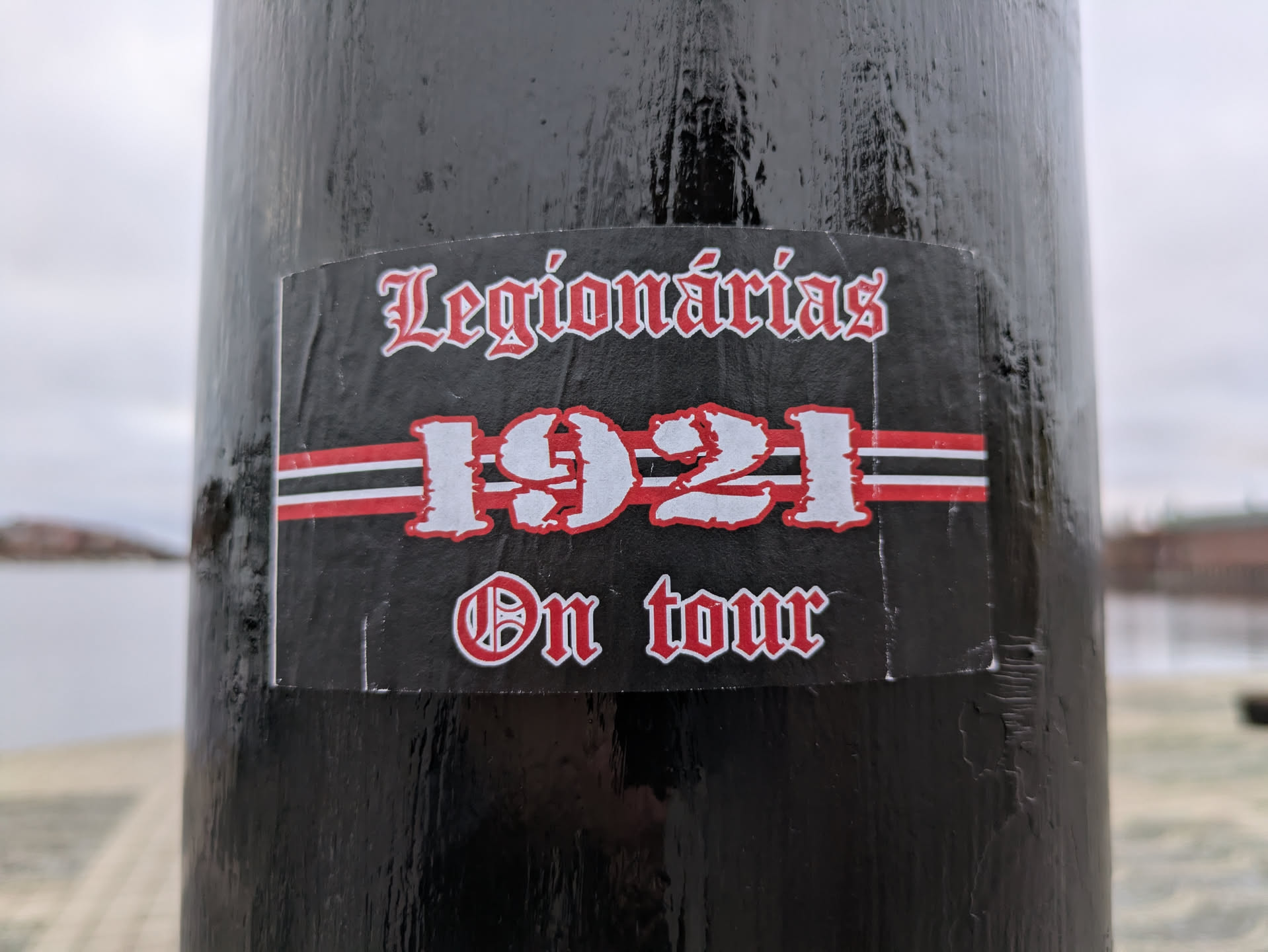 Black and red sticker with the text "Legionárias 1921 On Tour" in a gothic style font. The number 1921 is prominently displayed with red and white stripes beneath it.
