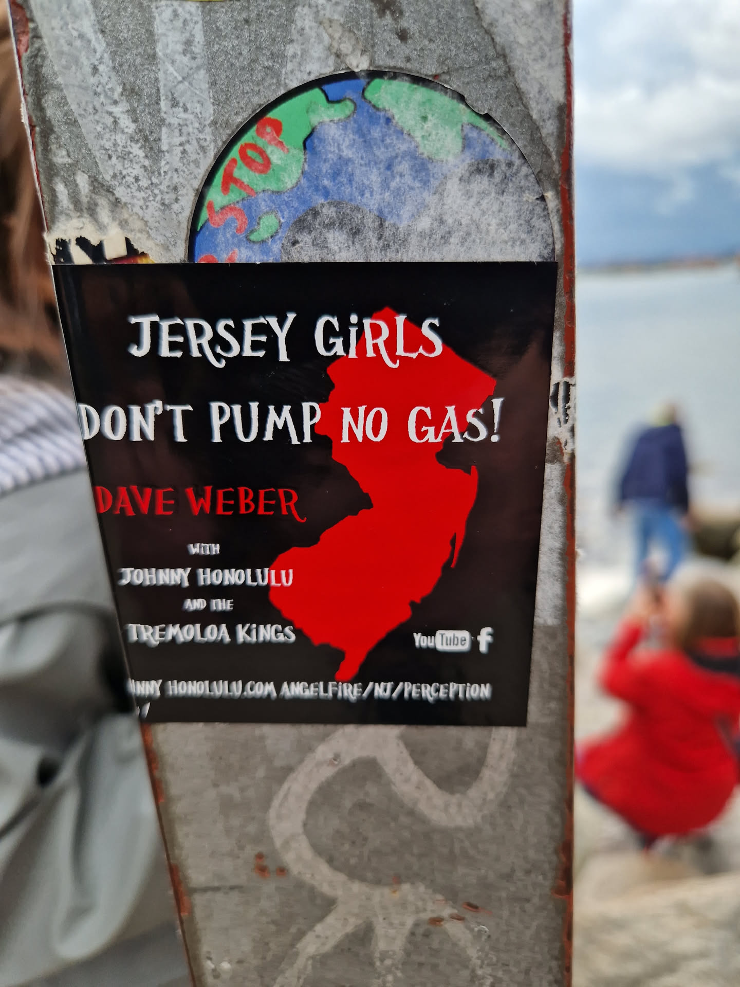 A black and red sticker promoting a music event featuring Dave Weber, Johnny Honolulu, and the Tremolo Kings.  The sticker includes a graphic of the state of New Jersey and social media links to YouTube and Facebook.