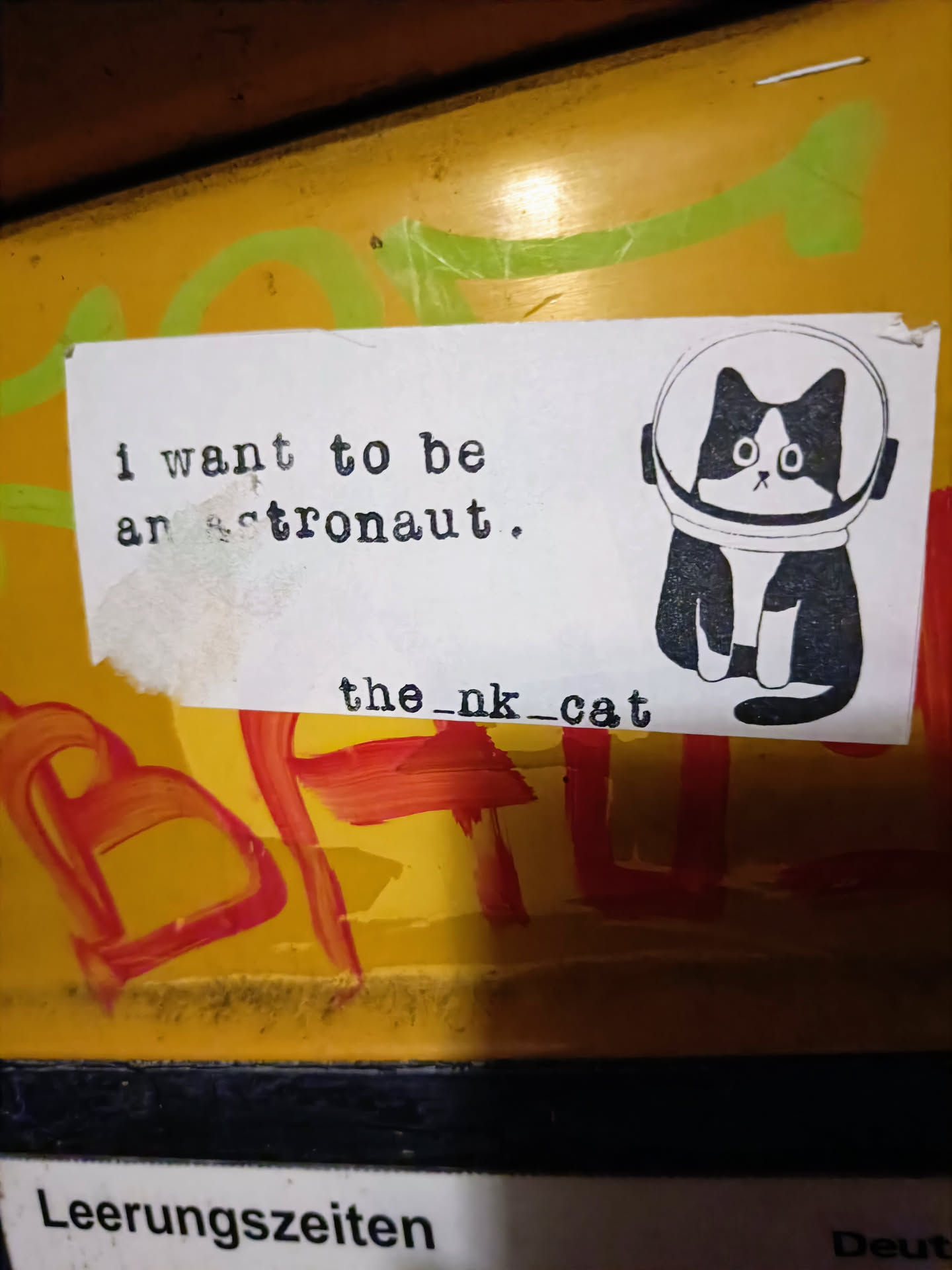 A sticker featuring a black and white cat wearing an astronaut helmet. The text 'I want to be an astronaut' is written above the cat, and 'the_nk_cat' is written below it.